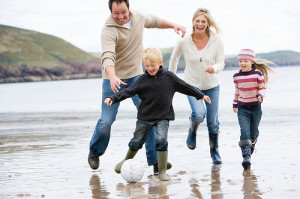 Family playing football on beach positive parenting